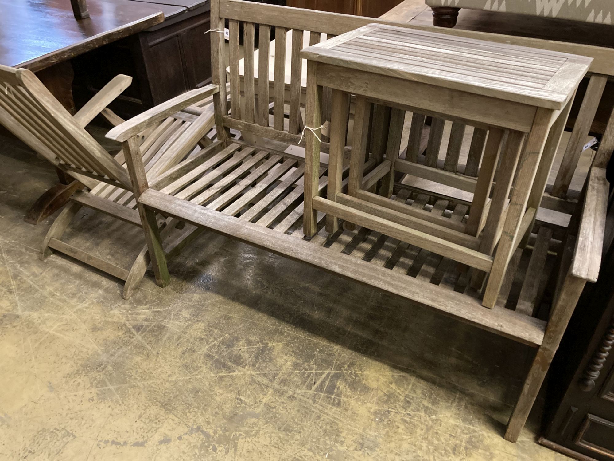 A weathered teak garden bench, length 129cm together with a teak steamer chair and nest of three teak rectangular garden tables